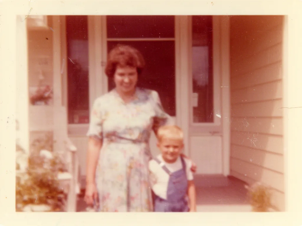 Original faded and scratched 1970s photo of a mother and a boy on a porch